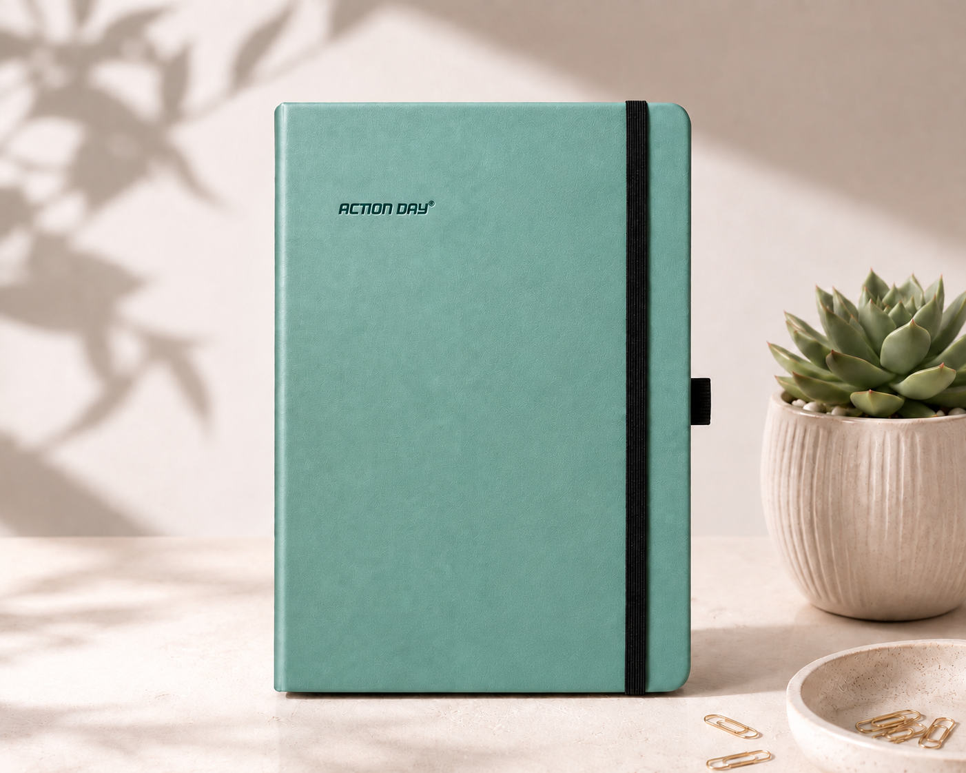 Action Day Yearly Planner in green, standing on a desk beside a succulent